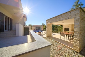 Enjoy al fresco dining and relaxation by the pool in this outdoor living area, featuring a barbecue area and comfortable seating.