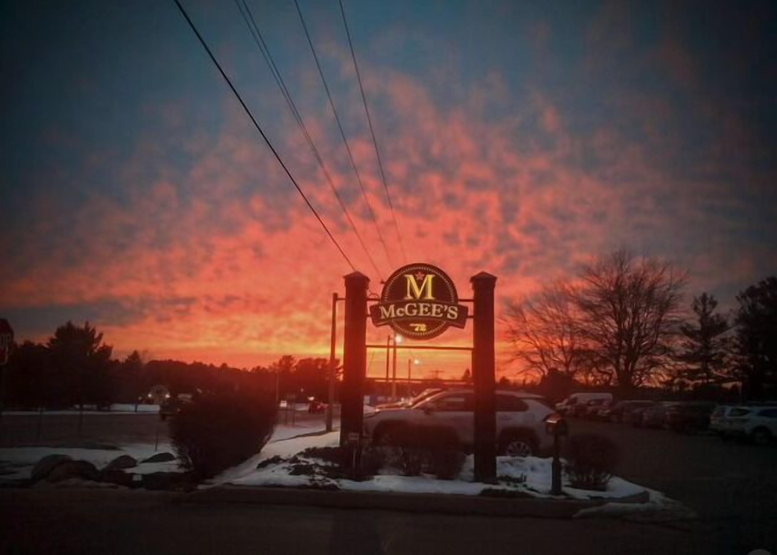Une enseigne du restaurant McGee's, avec un ciel au coucher du soleil en arrière-plan.