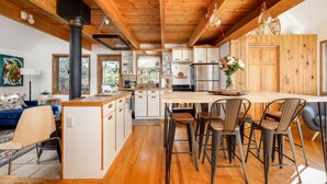 A modern kitchen with wooden beams, a central island, and bar stools. - Holiday Hills Escape | Fire Pit | AC | Mt. Holiday (Traverse City)