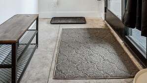 Un baño moderno con ducha, un banco, una alfombra y un perchero en la pared.