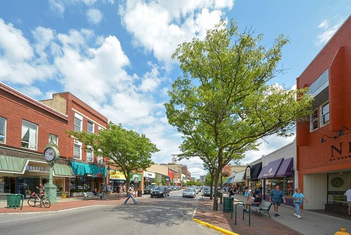 A street view with buildings, trees, and pedestrians.