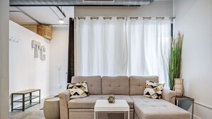 Una sala moderna con un sofá modular, una mesita blanca y una planta grande.