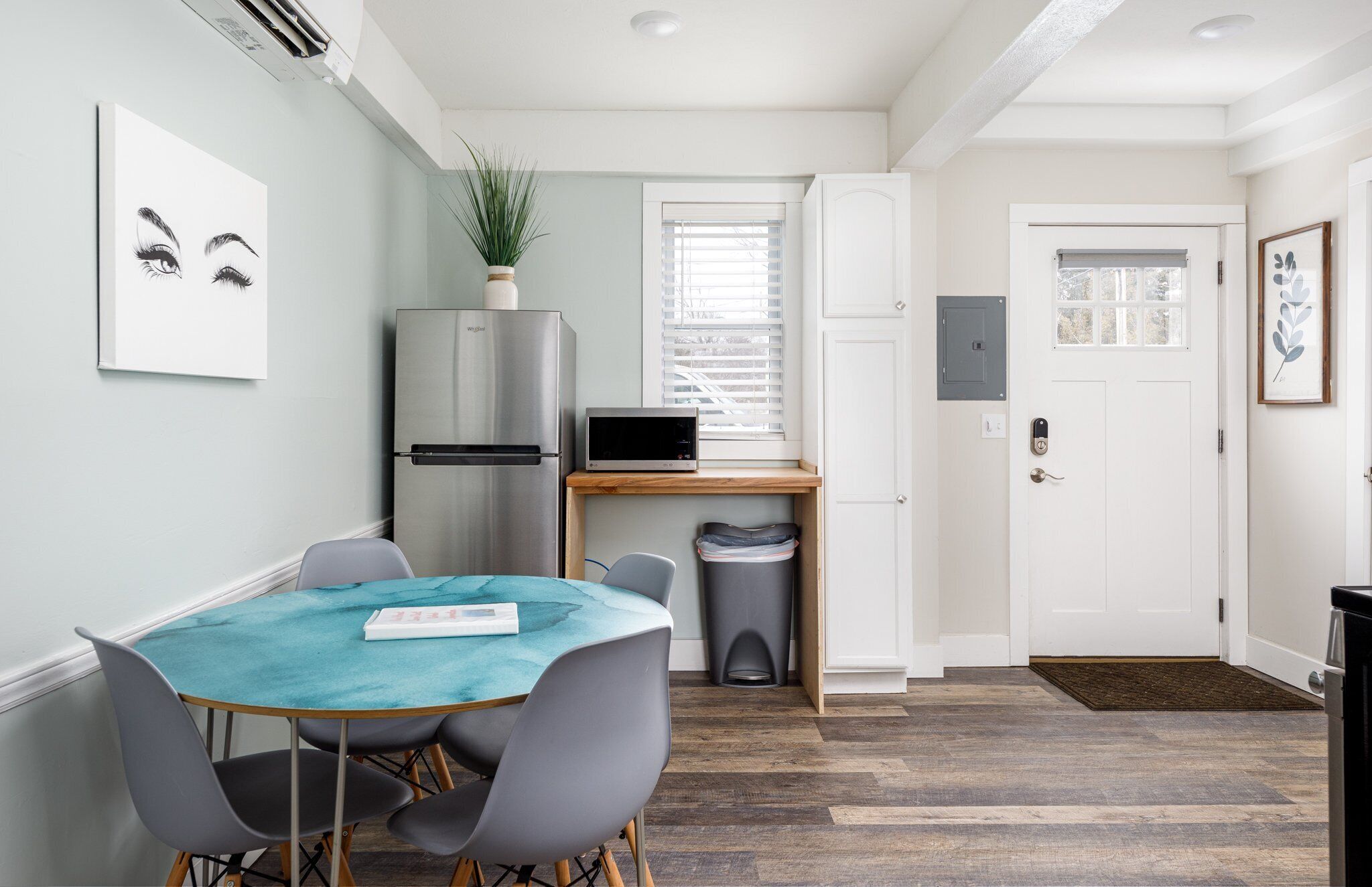 A compact kitchen with a refrigerator, microwave, and a small dining table with chairs.