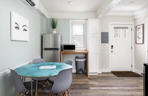 A compact kitchen with a refrigerator, microwave, and a small dining table with chairs.