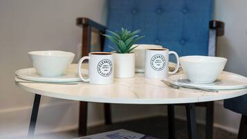A table with four white mugs, a small potted plant, and a bowl.