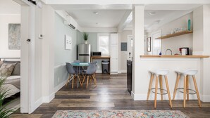 Une cuisine moderne avec un coin repas, un plancher en bois et un petit bar avec des tabourets.