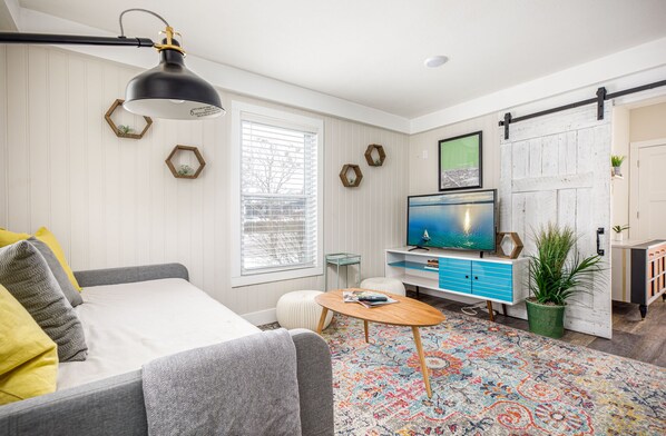 A modern living room with a sofa, a coffee table, a TV, and a colorful rug.
