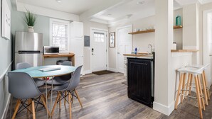 Une cuisine moderne avec un coin repas, comprenant un réfrigérateur, une cuisinière et des tabourets de bar.