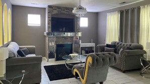 Uma sala de estar com lareira, dois sofás, uma mesa de centro e um candelabro.
