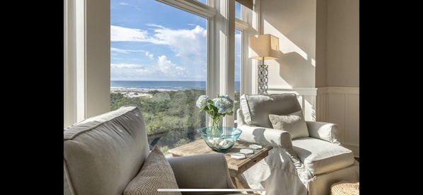 Enjoy ocean views from the large window in this stylish room, featuring a comfortable seating area and a floor lamp.