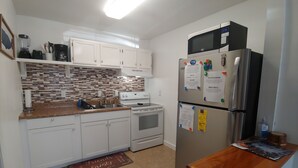 Een moderne keuken met witte kasten, een betegelde achterwand, een roestvrijstalen koelkast en een houten aanrecht.