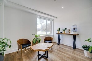 A room with a wooden floor, a table with a leather-like top, two chairs, a window, and a water dispenser. - Toronto Lakeshore Hotel (Mississauga)