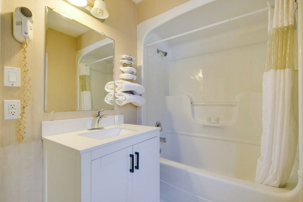 A bathroom with a sink, mirror, and a bathtub with a shower curtain.