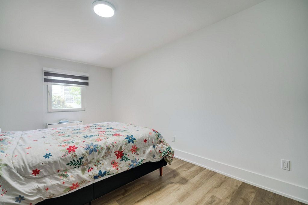 Un dormitorio con cama, ventana y lámpara en el techo.