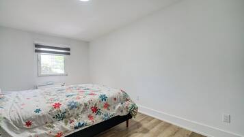 Un dormitorio con cama, ventana y lámpara en el techo.