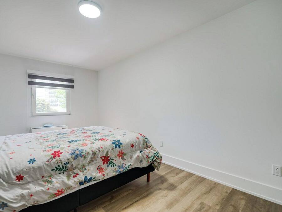 Un dormitorio con cama, ventana y lámpara en el techo.