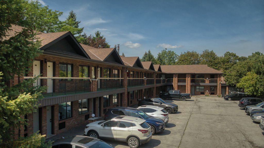 Un motel con varias habitaciones, estacionamiento y una galería techada.