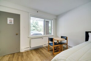A small room with a bed, a window, a table with two chairs, and a radiator. - Toronto Lakeshore Hotel (Mississauga)