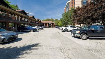 A parking lot with multiple cars, a building with a brick facade, and a taller building in the background.