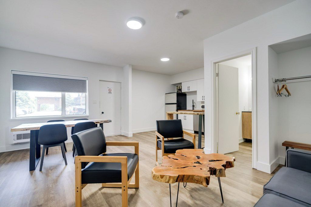 A modern living room with a dining area, a kitchen, and a view of the outside.
