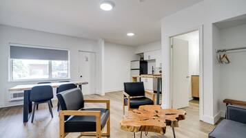 A modern living room with a dining area, a kitchen, and a view of the outside.