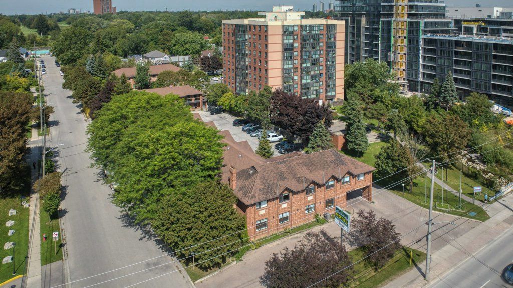 A multi-story building with a brick facade, surrounded by trees and a clear sky.