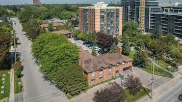 A multi-story building with a brick facade, surrounded by trees and a clear sky.