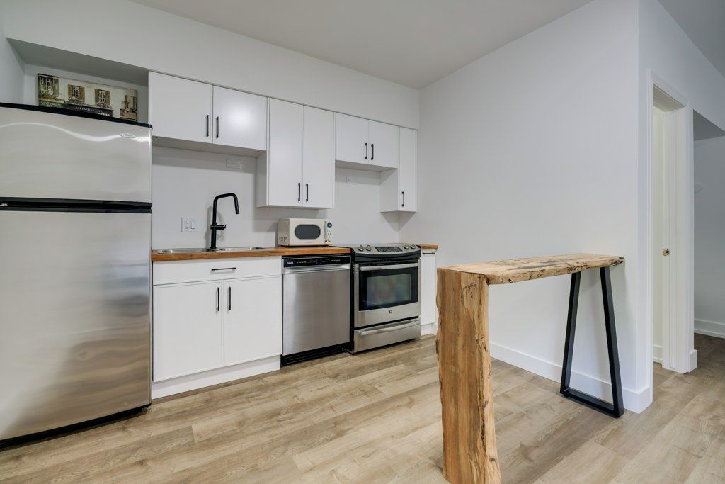 A modern kitchen with white cabinets, stainless steel appliances, and a wooden table.