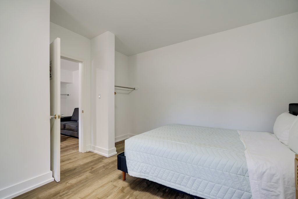 Une chambre à coucher avec un lit, une porte donnant sur une autre pièce et un placard visible.