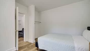 Une chambre à coucher avec un lit, une porte donnant sur une autre pièce et un placard visible.