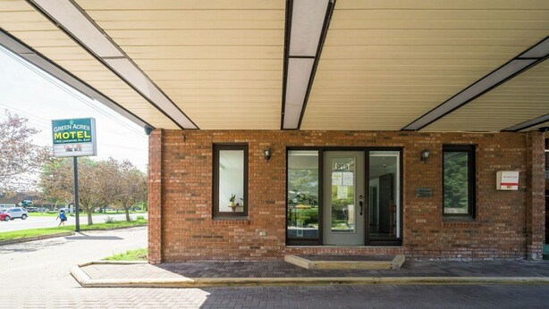 A brick motel with a covered entrance, a signboard, and a paved driveway. - Toronto Lakeshore Hotel (Mississauga)
