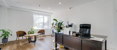 A modern office space with a desk, chairs, and a large window.