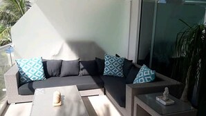 A modern outdoor seating area with a sofa and two side tables, one with a decorative item.