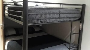 A bunk bed with a metal frame and grey bedding.