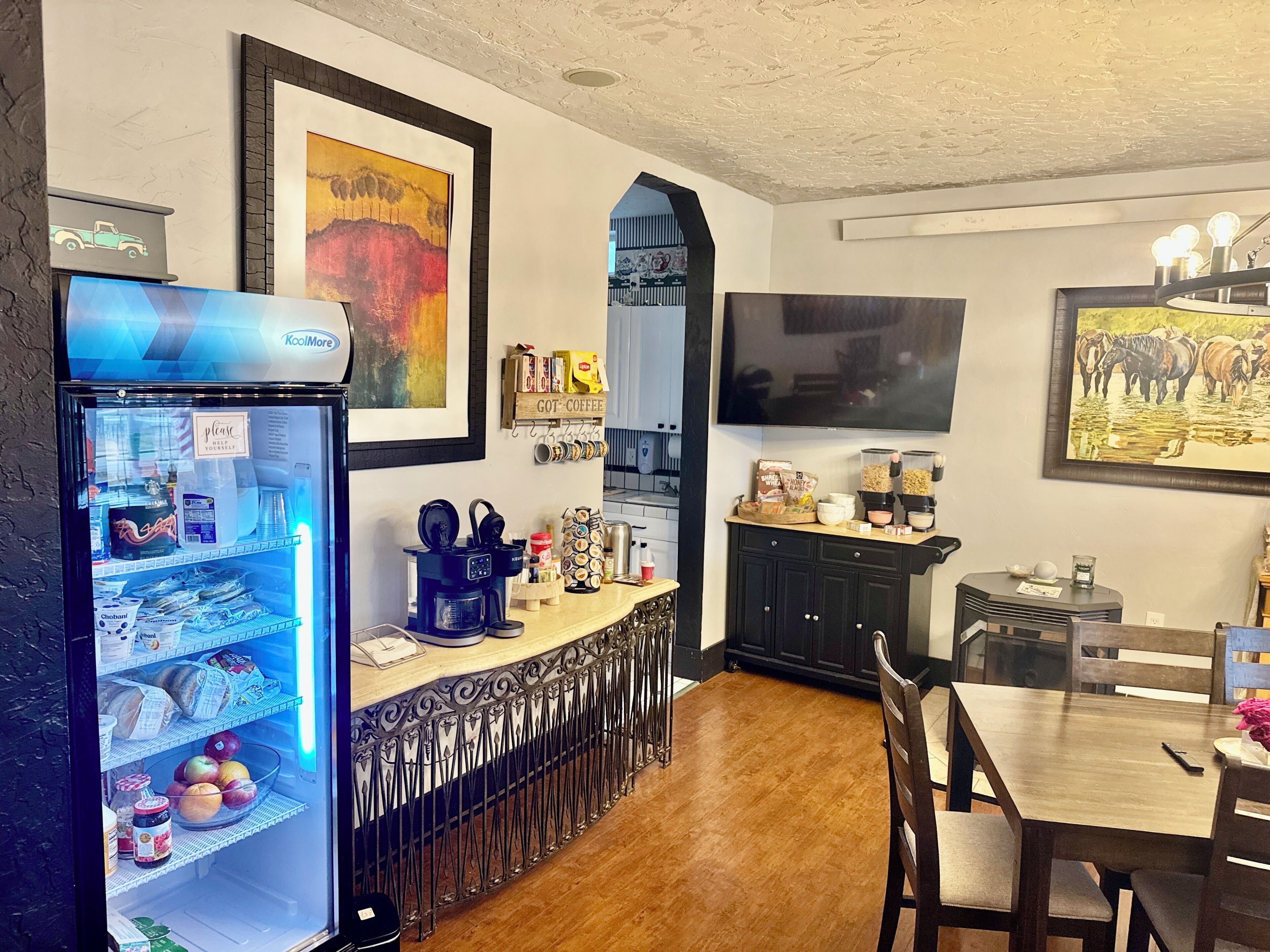 A kitchen with a coffee machine, a refrigerator, and a dining area with a table and chairs.