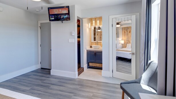 Een moderne hotelkamer met een groot bed, een zithoek, een badkamer met wastafel en een aan de muur bevestigde televisie.