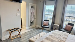 Een moderne slaapkamer met een bed, twee stoelen, een bankje, een televisie en uitzicht op de omgeving.