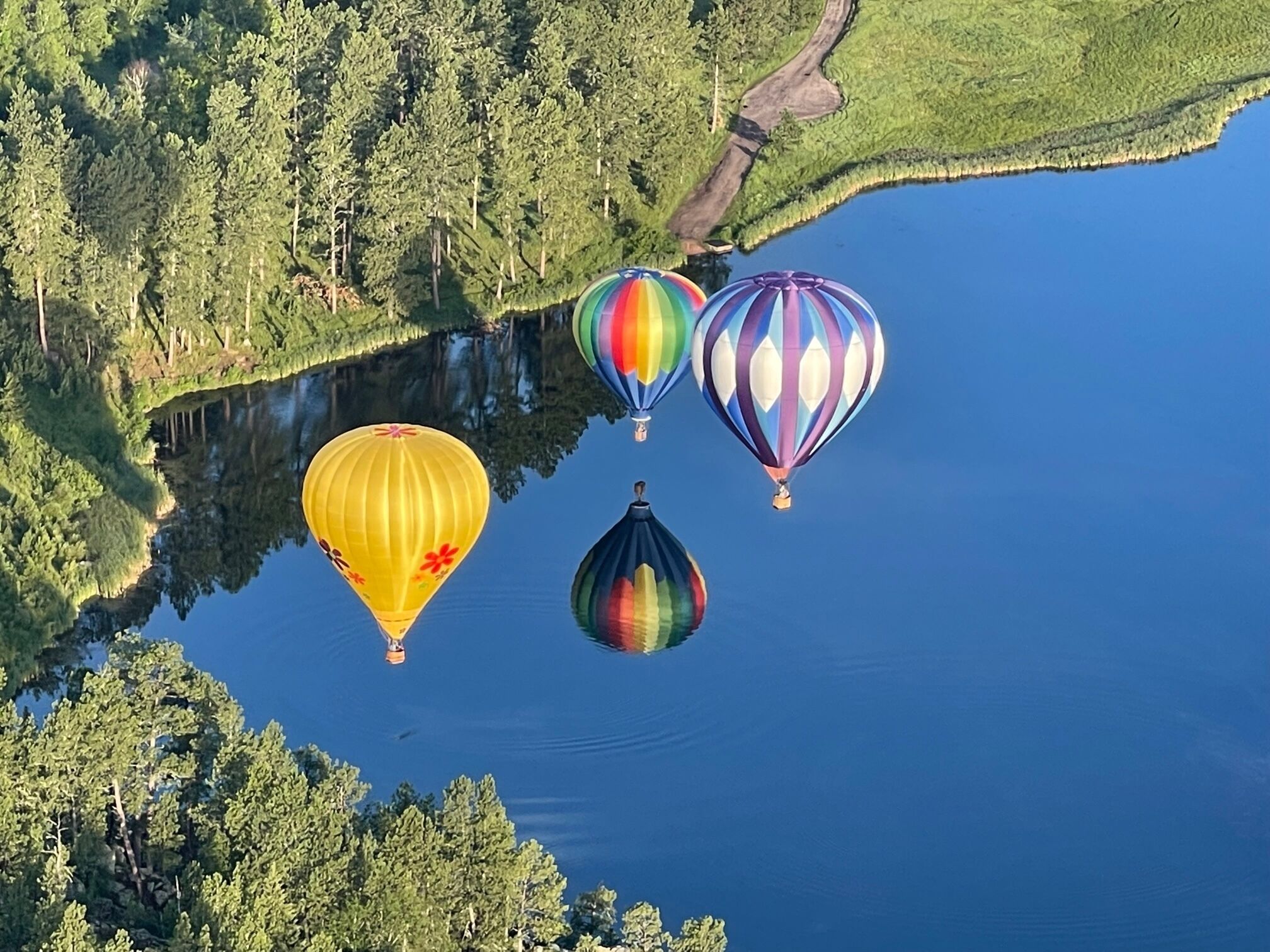 A lake with four hot air balloons.