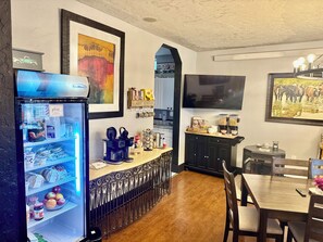 Une cuisine équipée d’une machine à café, d’un réfrigérateur et d’un coin repas avec une table et des chaises.