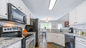 Una cucina moderna con mobili bianchi, elettrodomestici in acciaio inossidabile e un piano di lavoro in granito.