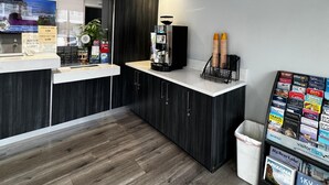 A modern lobby with a reception desk, a coffee machine, a trash bin, and a magazine rack. - Friendship Motor Inn (Los Angeles)