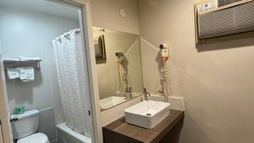 A bathroom with a toilet, shower, and sink.