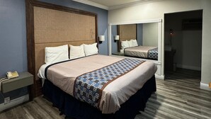 A hotel room with a large bed, a nightstand with a phone, and a mirror above the bed. - Friendship Motor Inn (Los Angeles)