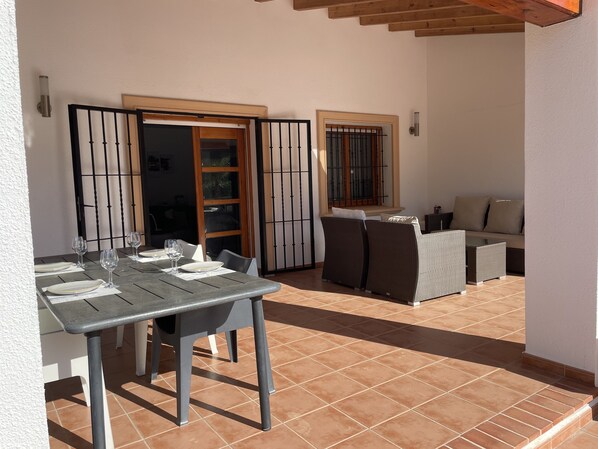 A patio with a dining table set for four, two wicker sofas, and a window with a metal grill. - Stunning Villa (Sleeps 8) Jávea, Costa Blanca, closes to beaches (Javea)