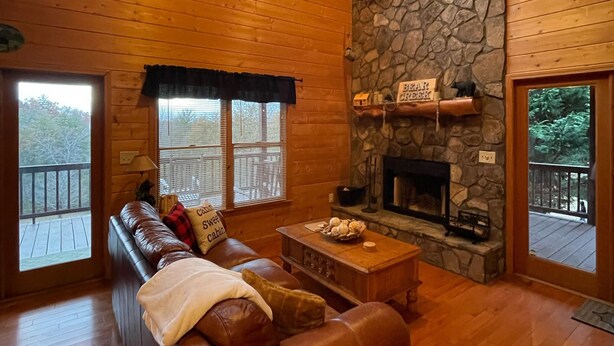 A cozy cabin interior with a stone fireplace, wooden walls, and a leather sofa. - Spacious Blue Ridge Mountain Cabin. Great location & beautiful views!  (Morganton)