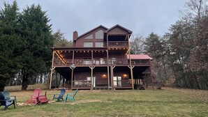 A two-story wooden cabin with a balcony, surrounded by trees. - Spacious Blue Ridge Mountain Cabin. Great location & beautiful views!  (Morganton)
