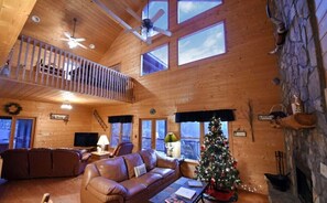 A cozy cabin interior with a wooden interior, a fireplace, a Christmas tree, and a balcony with a railing. - Spacious Blue Ridge Mountain Cabin. Great location & beautiful views!  (Morganton)