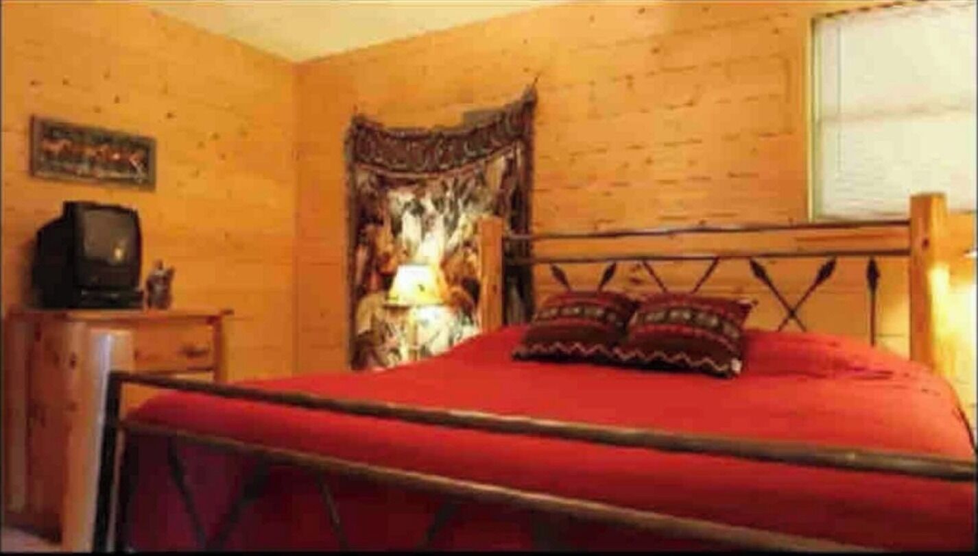 A room with a bed, a television, and a lamp.