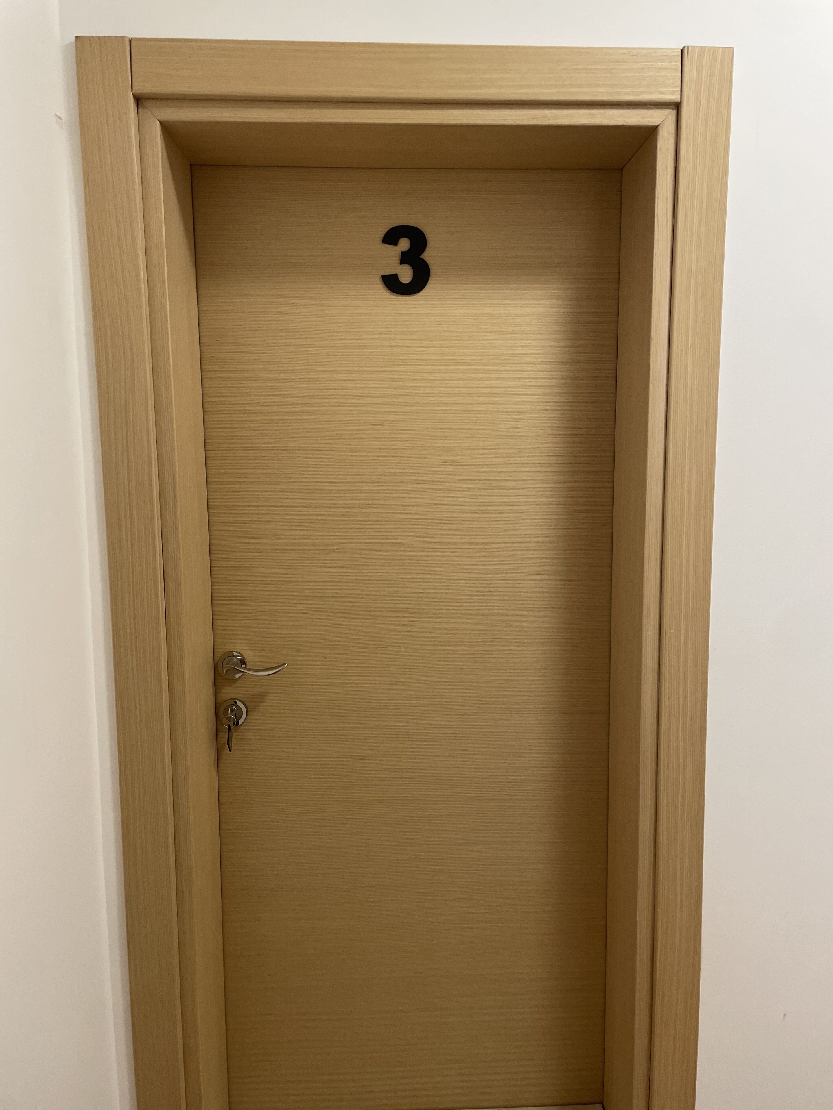 Une porte en bois portant le numéro 3, avec une serrure et une poignée.