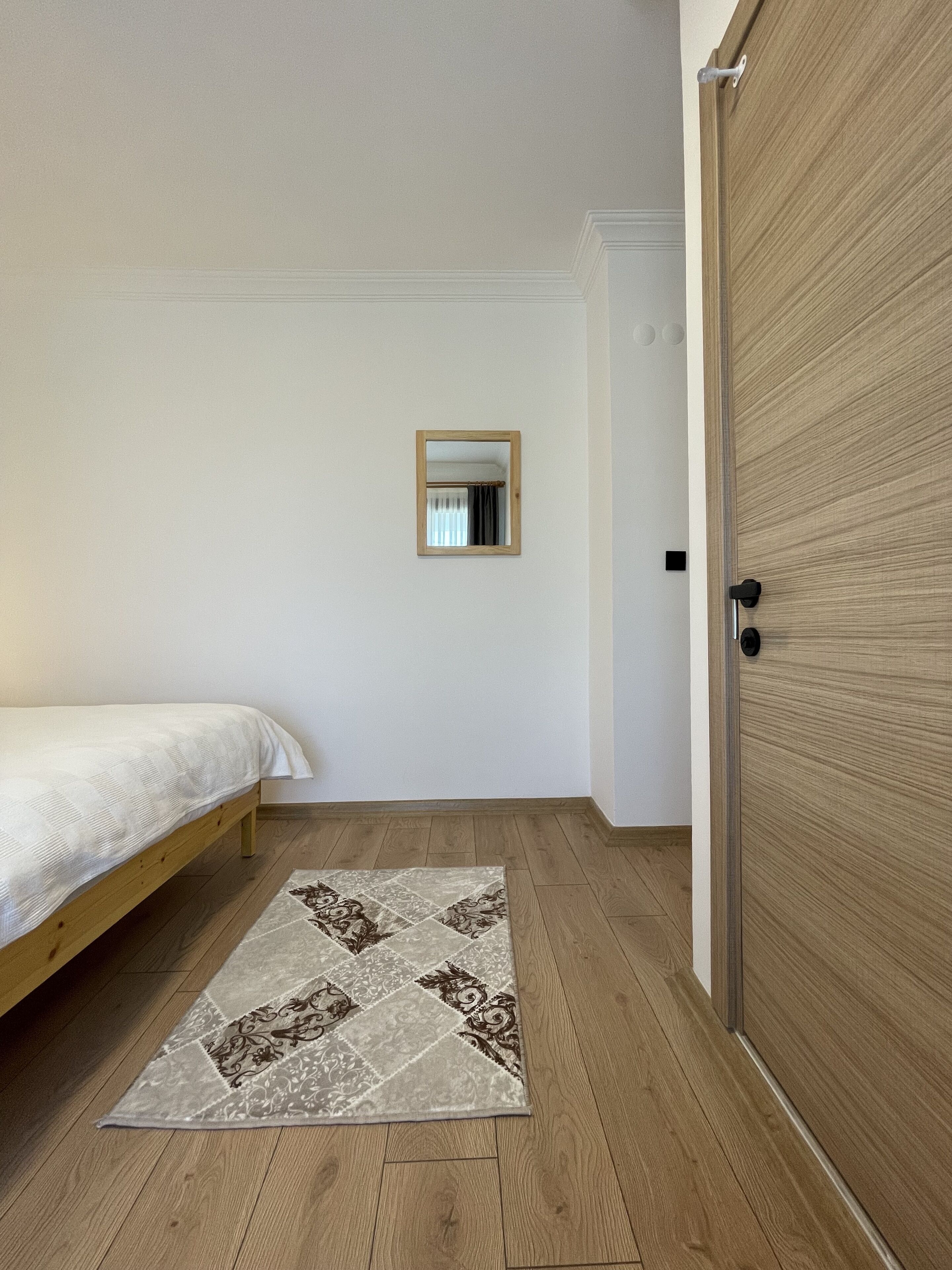 Une chambre à coucher avec un lit, une armoire en bois, un miroir et un tapis à motifs.